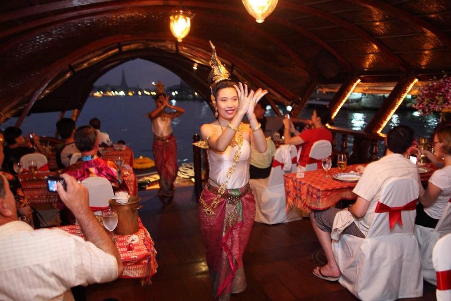 Tourists have a dinner cruise while enjoying a traditional dance performance