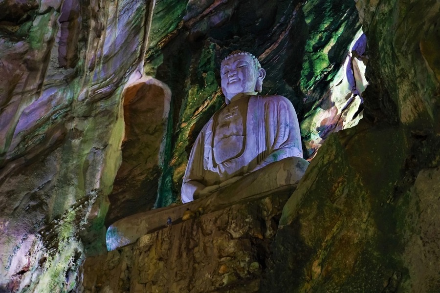 The focal point within the cave is the imposing statue of Shakyamuni Buddha