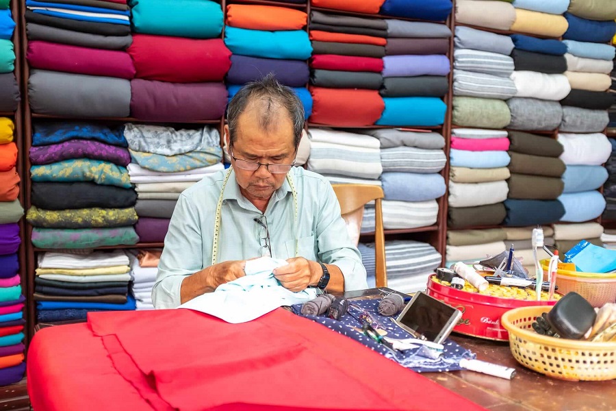 A tailor deeply focused on his workbench in Hoi An