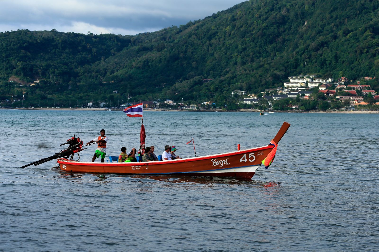 A colorful long-tail boat carries tourists to sightsee amidst the stunning waters of Thailand.