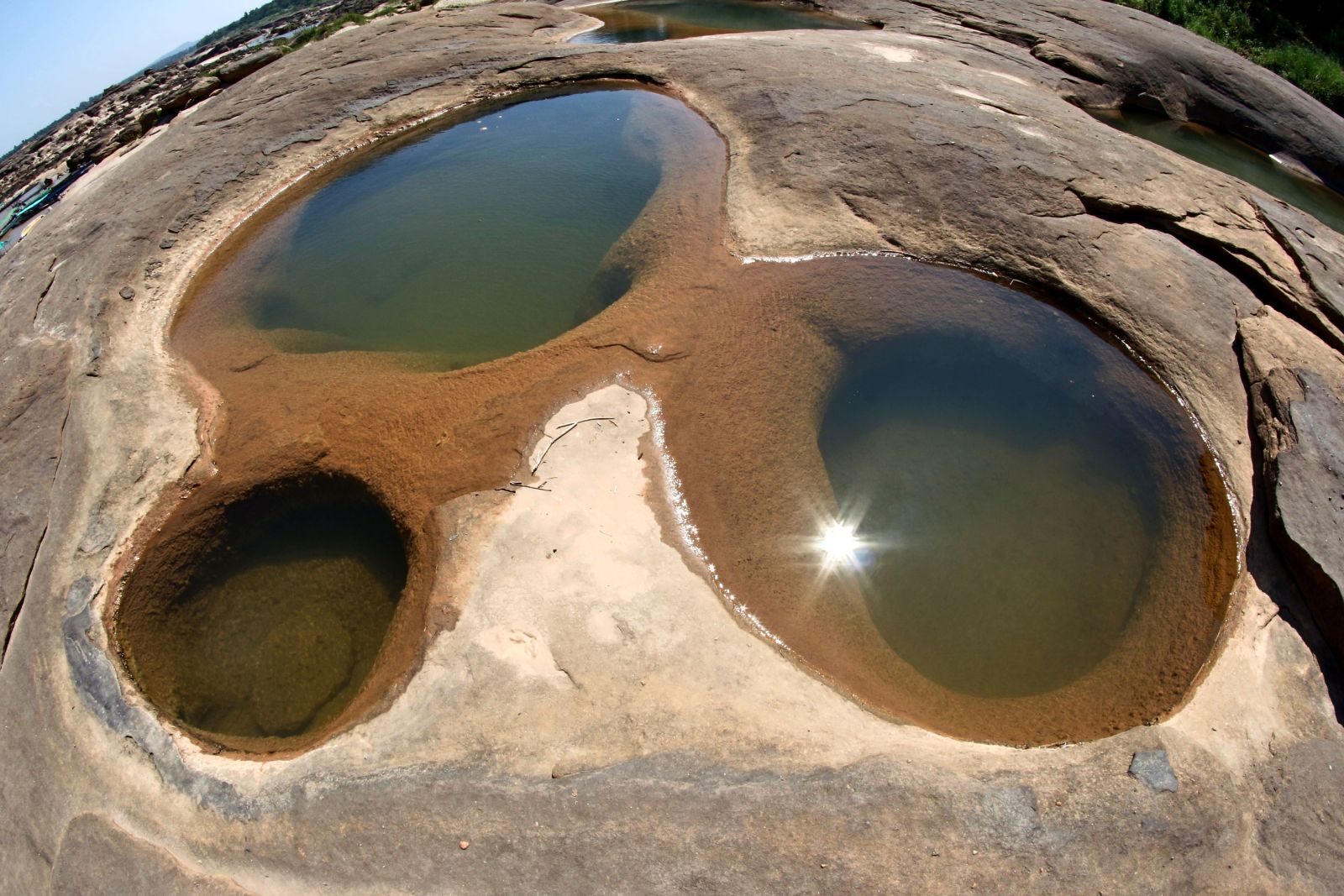 Stunning natural rock pools reflect the sunlight within the outdoor landscape.
