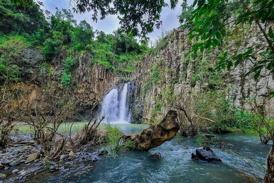 Vuc Hom Waterfall flows gently through a lush, untouched forest