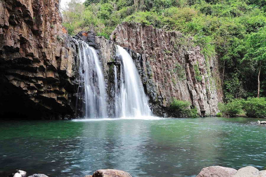 Vuc Hom Waterfall cascades gracefully into a serene emerald pool, surrounded by striking rock formations