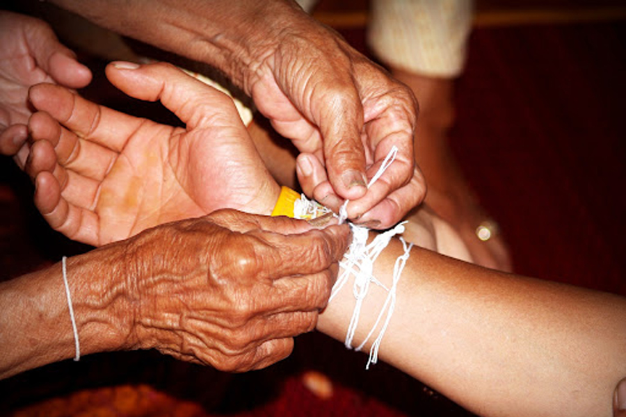 Tying the white string during Baci Ceremony