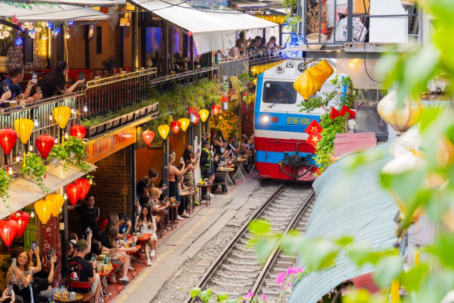 The train passes closely by the cafés 