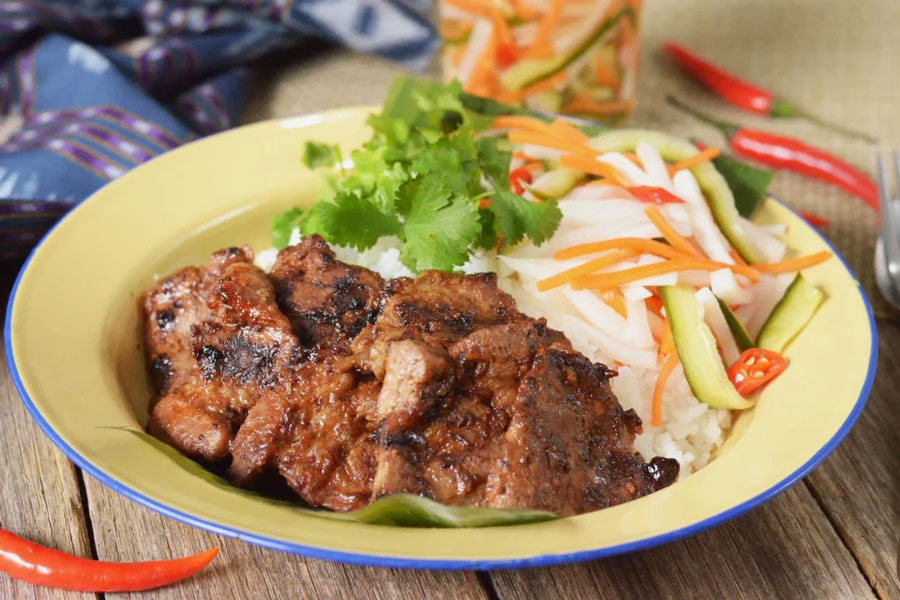A popular breakfast dish, Bai Sach Chrouk consists of grilled pork served over broken rice, topped with a light and flavorful sauce