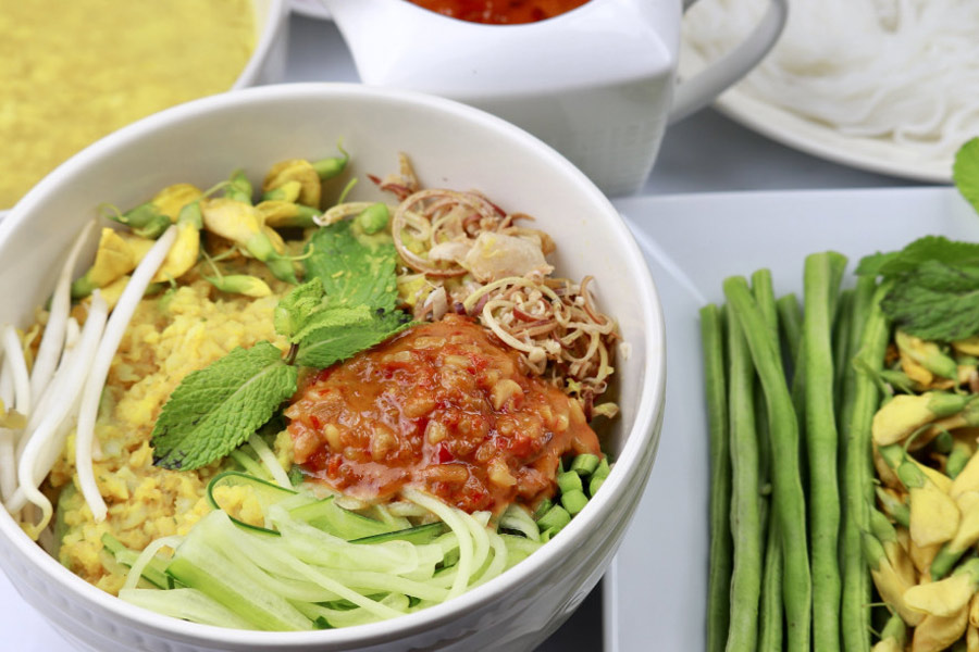 Nom Banh Chok is a dish made with fresh rice noodles topped with a fish-based green curry gravy and an assortment of raw vegetables