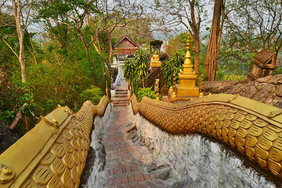 Wat Tham Phousi, located halfway to Phou Si’s summit (Cre: RenownTravel)