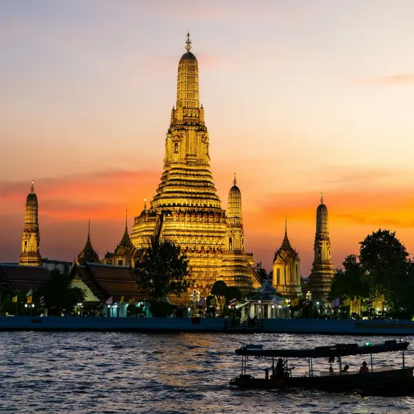 A longtail boat on the Chao Phraya at golden hour, Wat Arun behind